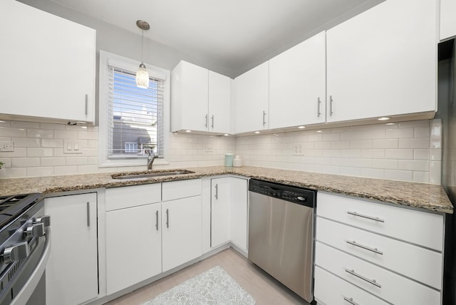 kitchen featuring light stone counters, white cabinets, stainless steel appliances, and a sink