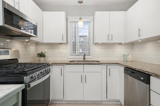 kitchen with white cabinets, light stone counters, appliances with stainless steel finishes, and a sink