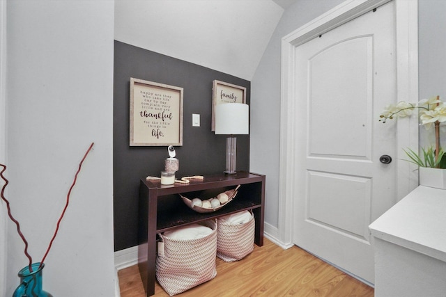 interior space featuring lofted ceiling, light wood-style flooring, and baseboards