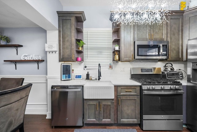 kitchen featuring a wainscoted wall, stainless steel appliances, light countertops, open shelves, and a sink