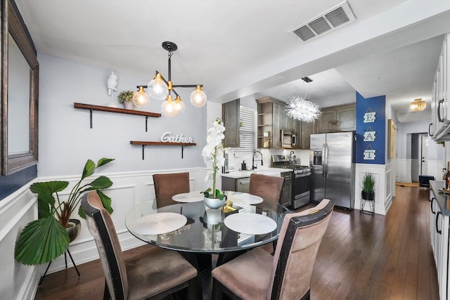 dining area with an inviting chandelier, visible vents, dark wood-style flooring, and wainscoting