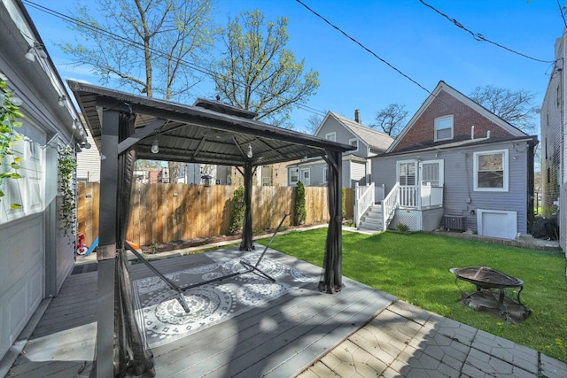 back of house with a yard, a gazebo, an outdoor fire pit, fence, and a deck