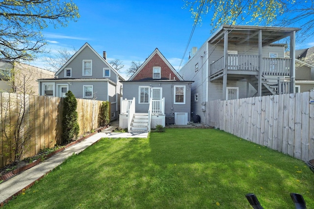 back of property with a yard, central AC, and a fenced backyard