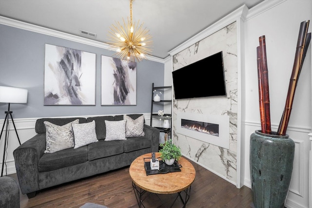 living room featuring a fireplace, ornamental molding, a chandelier, and wood finished floors