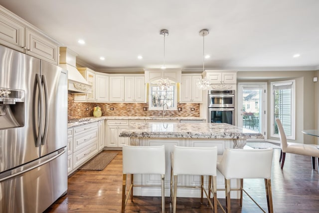 kitchen with stainless steel appliances, premium range hood, dark wood-type flooring, a sink, and decorative backsplash