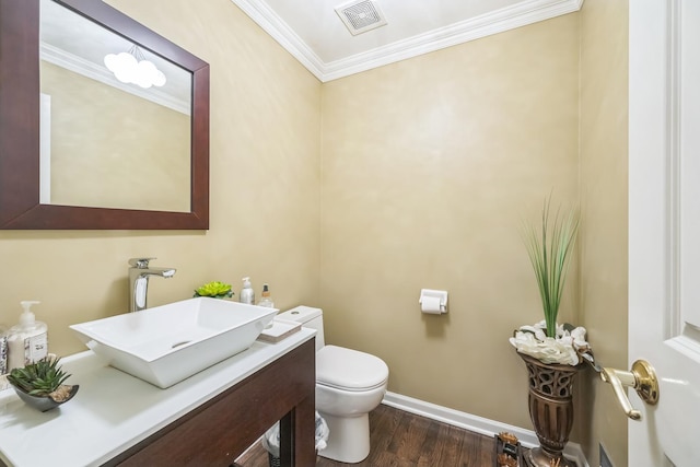 half bath featuring visible vents, toilet, ornamental molding, wood finished floors, and vanity