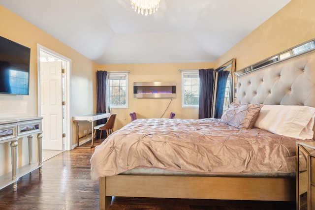 bedroom featuring vaulted ceiling, wood finished floors, and an inviting chandelier