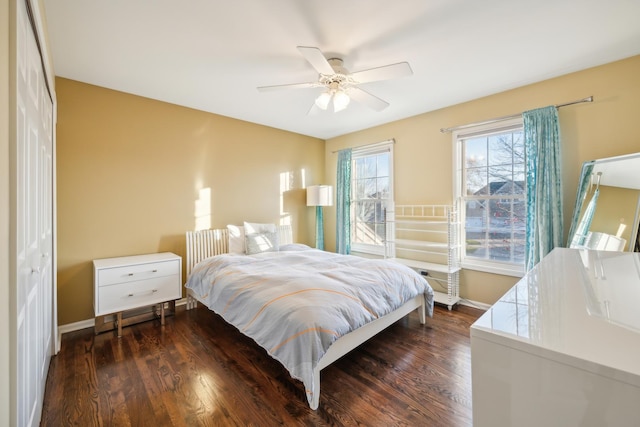 bedroom with a ceiling fan, baseboards, and dark wood-type flooring