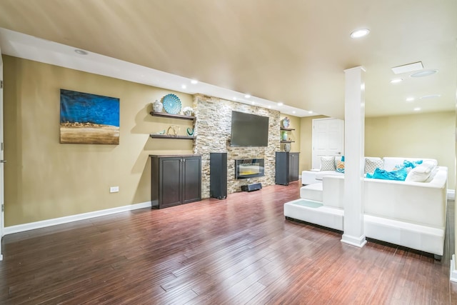 living area with recessed lighting, baseboards, wood finished floors, and a stone fireplace