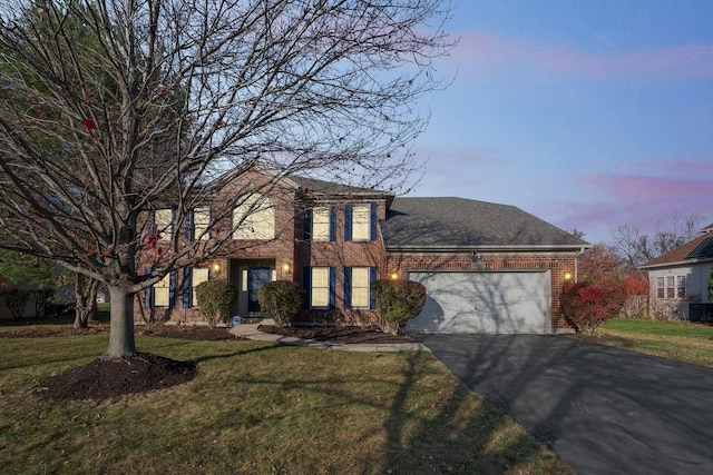 view of front of house featuring driveway, a lawn, roof with shingles, an attached garage, and brick siding