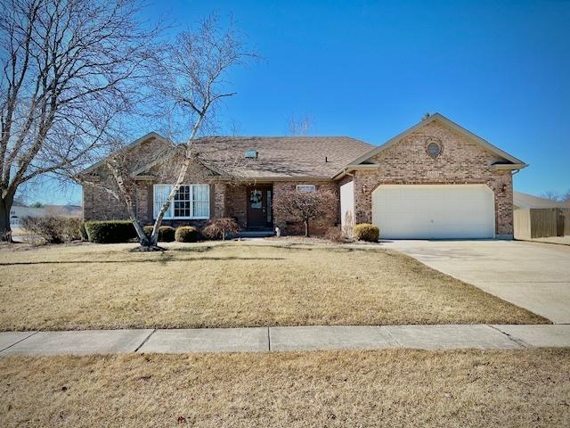 ranch-style house featuring a front yard, concrete driveway, brick siding, and an attached garage