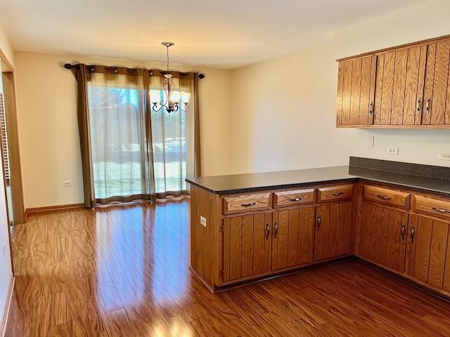 kitchen featuring dark countertops, dark wood-style floors, a peninsula, and brown cabinetry