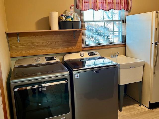 washroom featuring washer and dryer, laundry area, and light wood finished floors