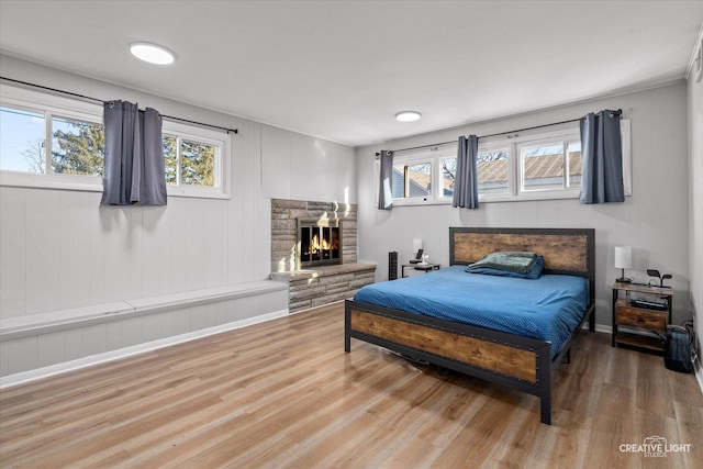 bedroom with multiple windows, a fireplace, and wood finished floors