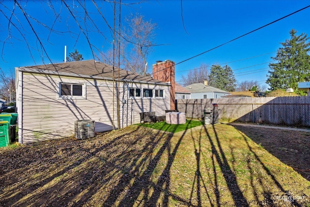 rear view of property featuring fence, a chimney, and a lawn