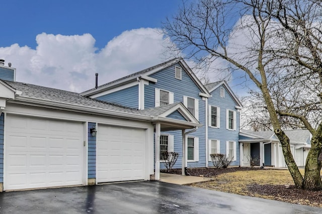 traditional-style house featuring driveway, a shingled roof, and an attached garage