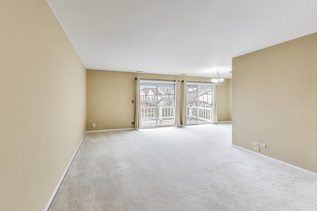 spare room with baseboards, light colored carpet, and an inviting chandelier