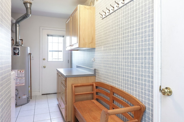 kitchen featuring water heater, light tile patterned floors, and light brown cabinetry