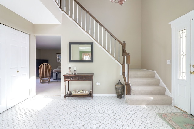 carpeted foyer featuring stairway, baseboards, and a towering ceiling