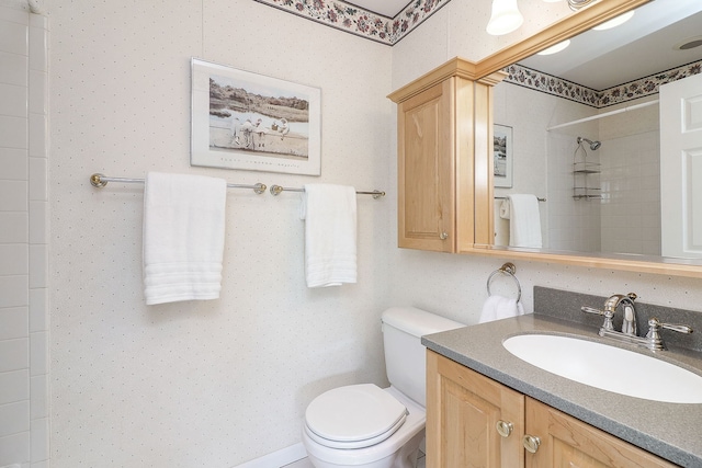 full bathroom featuring tiled shower, toilet, and vanity