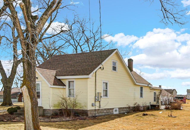 view of side of home featuring a shingled roof and a chimney