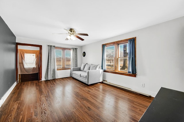 unfurnished room featuring a baseboard radiator, ceiling fan, baseboards, and wood finished floors