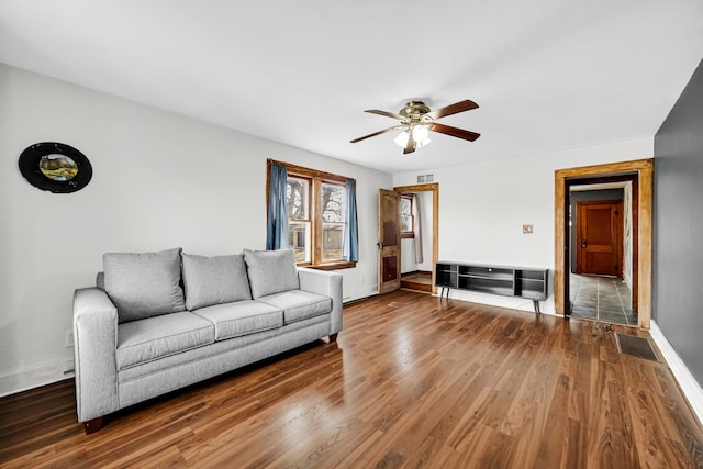 unfurnished living room featuring baseboards, visible vents, a ceiling fan, and wood finished floors