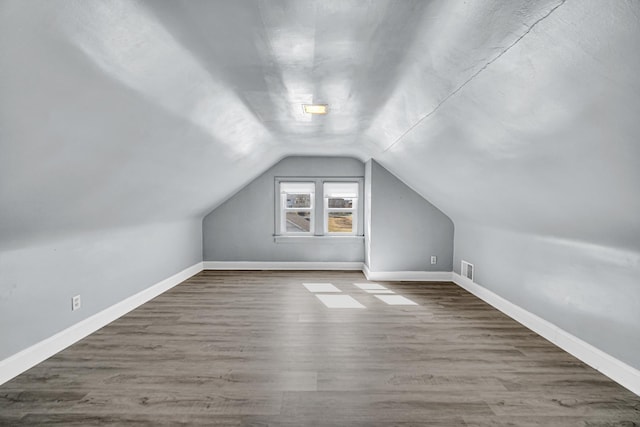 additional living space featuring lofted ceiling, wood finished floors, visible vents, and baseboards