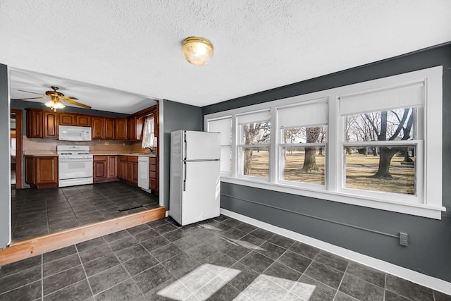 kitchen with brown cabinets, light countertops, a textured ceiling, white appliances, and baseboards