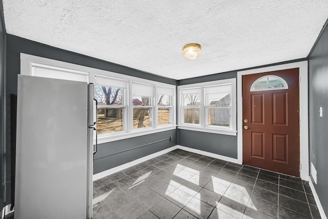 foyer with a wealth of natural light, a textured ceiling, and baseboards