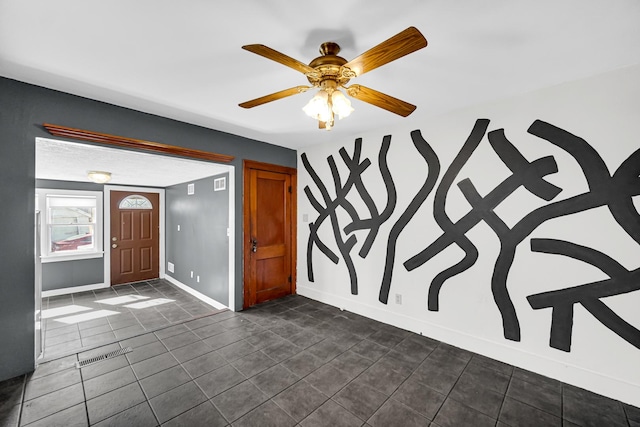 foyer featuring ceiling fan, baseboards, and dark tile patterned flooring