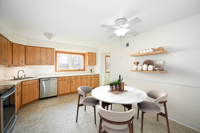 kitchen with a sink, tasteful backsplash, a ceiling fan, light countertops, and appliances with stainless steel finishes