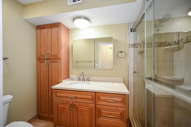 bathroom with toilet, vanity, a shower stall, and visible vents