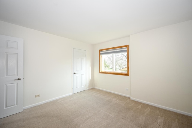 unfurnished room featuring baseboards and light colored carpet