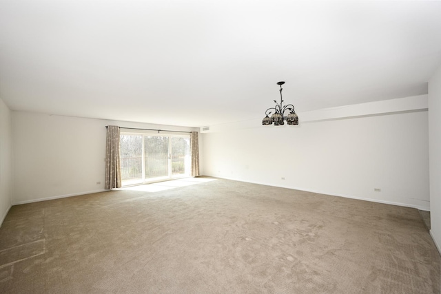spare room featuring visible vents, baseboards, a notable chandelier, and light carpet