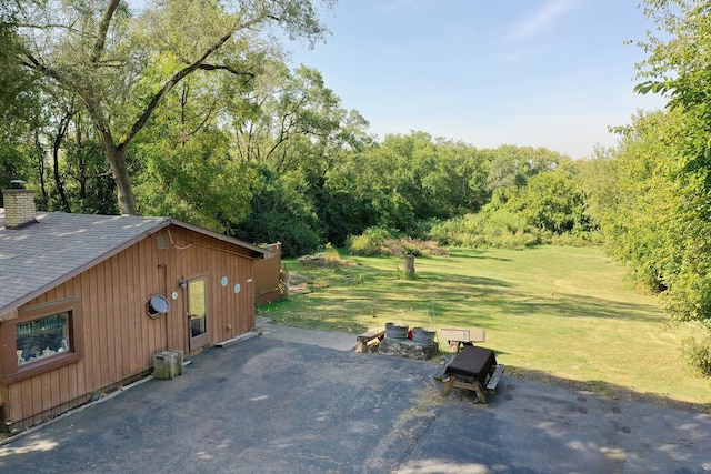 exterior space featuring a yard, a shingled roof, and a chimney