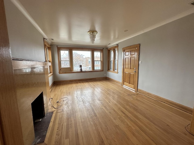 unfurnished living room featuring visible vents, baseboards, crown molding, light wood-style floors, and a fireplace