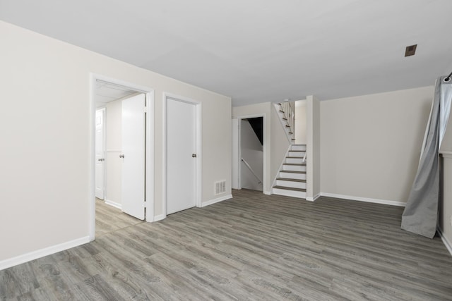 below grade area featuring stairs, wood finished floors, visible vents, and baseboards