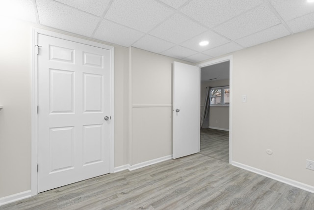 interior space featuring recessed lighting, a drop ceiling, light wood-style flooring, and baseboards