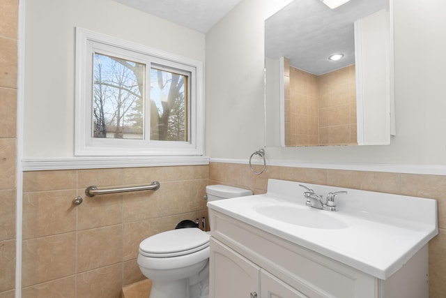 bathroom with wainscoting, tile walls, toilet, and vanity