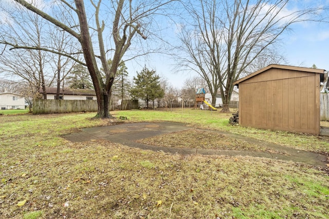 view of yard featuring an outbuilding, a shed, a playground, and fence