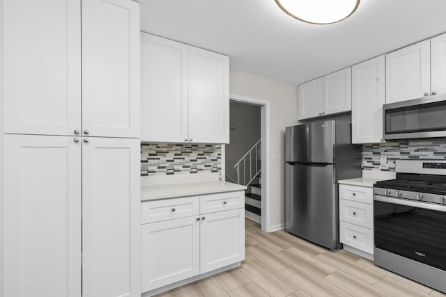 kitchen featuring stainless steel appliances, white cabinets, light countertops, and decorative backsplash