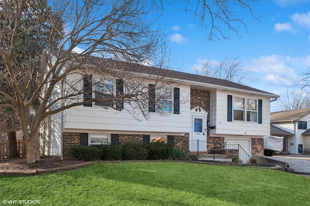 split foyer home with a garage, brick siding, and a front lawn