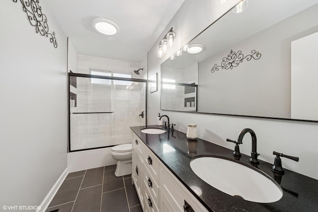 full bath featuring toilet, tile patterned flooring, double vanity, and a sink