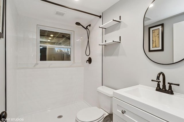 full bathroom featuring visible vents, a tile shower, vanity, and toilet