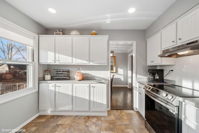 kitchen with under cabinet range hood, white cabinetry, baseboards, stainless steel electric stove, and tasteful backsplash