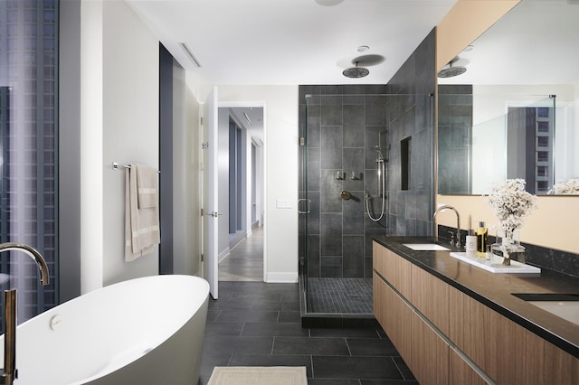 bathroom with double vanity, a stall shower, tile patterned floors, a freestanding bath, and a sink