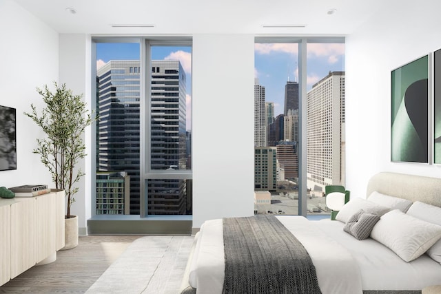 bedroom with floor to ceiling windows, a city view, and wood finished floors