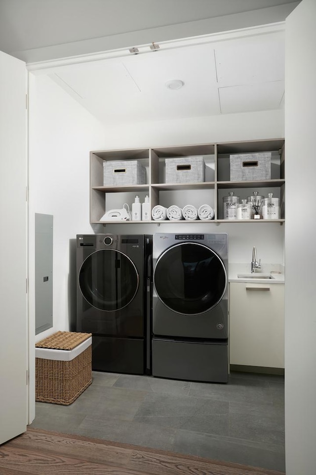 clothes washing area featuring washing machine and dryer, laundry area, a sink, and wood finished floors