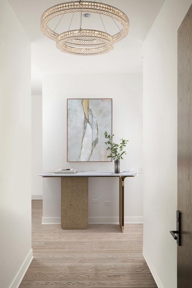 corridor featuring light wood-type flooring and baseboards